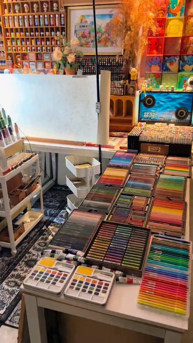 Numerous organized sets of colored pencils and art supplies spread across a white table in a craft room.