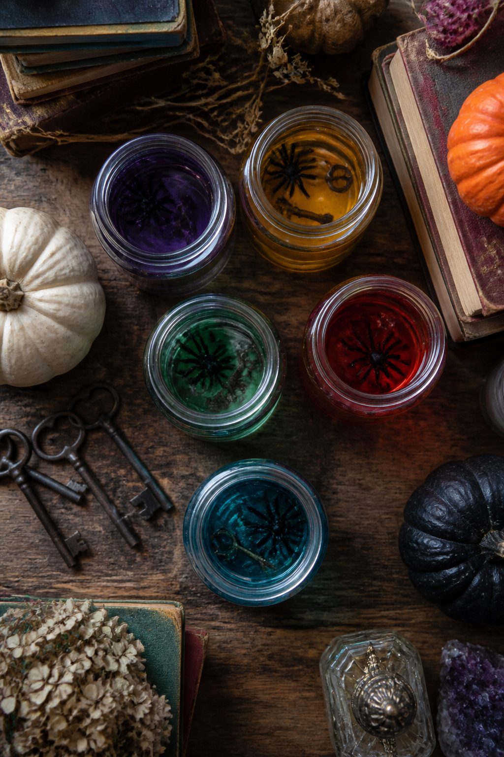 15 DIY Halloween Decorations for a Spooky 2026 9 Mason jars filled with colored water and floating Halloween-themed objects.
