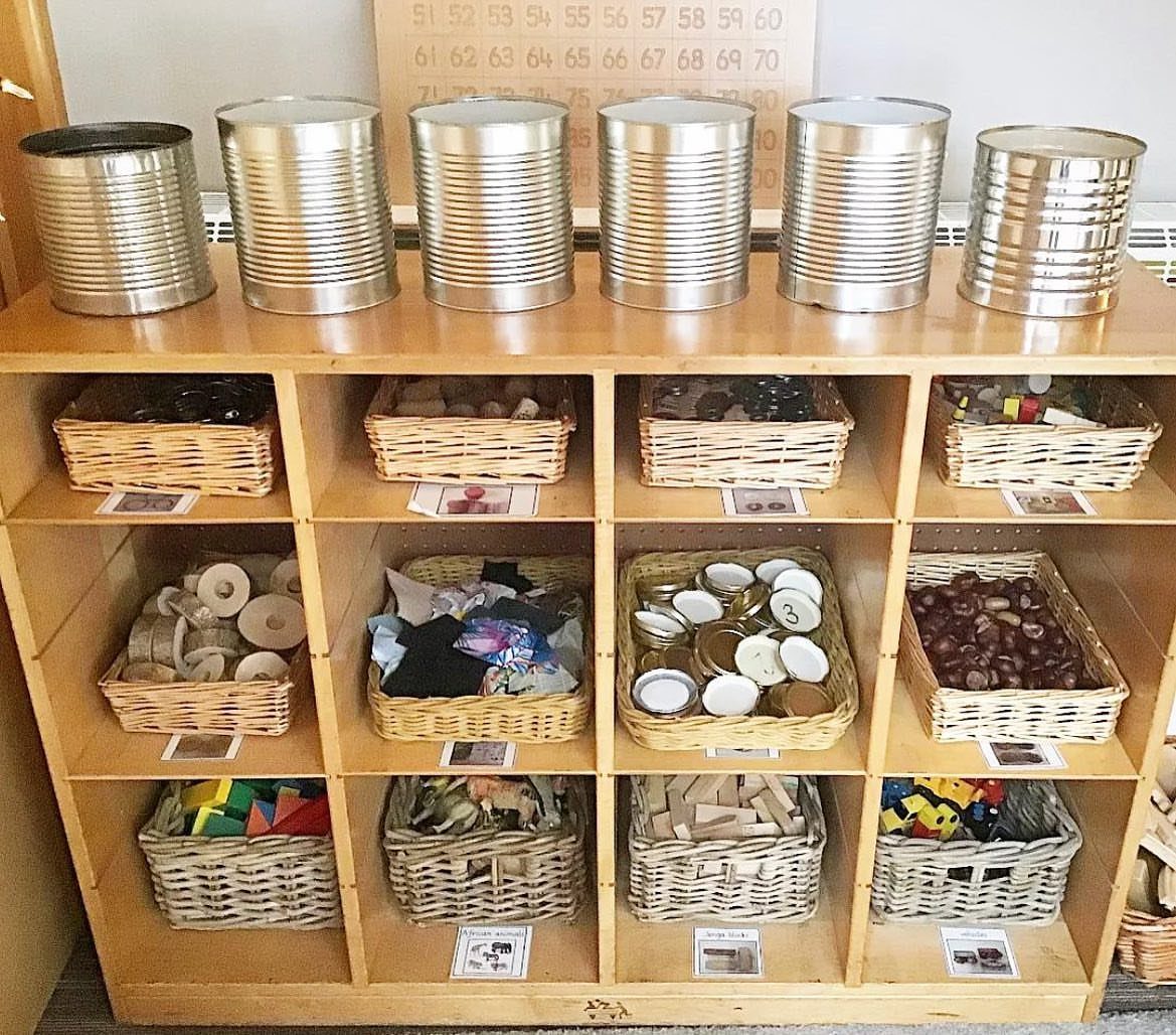 Wooden cubby shelf containing various wicker baskets with small labels on each basket.