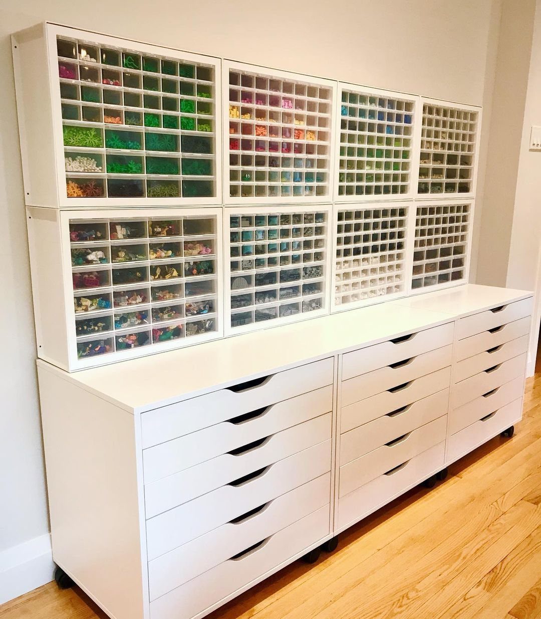 White stackable drawer units filled with colorful LEGO pieces sitting atop a large white dresser.