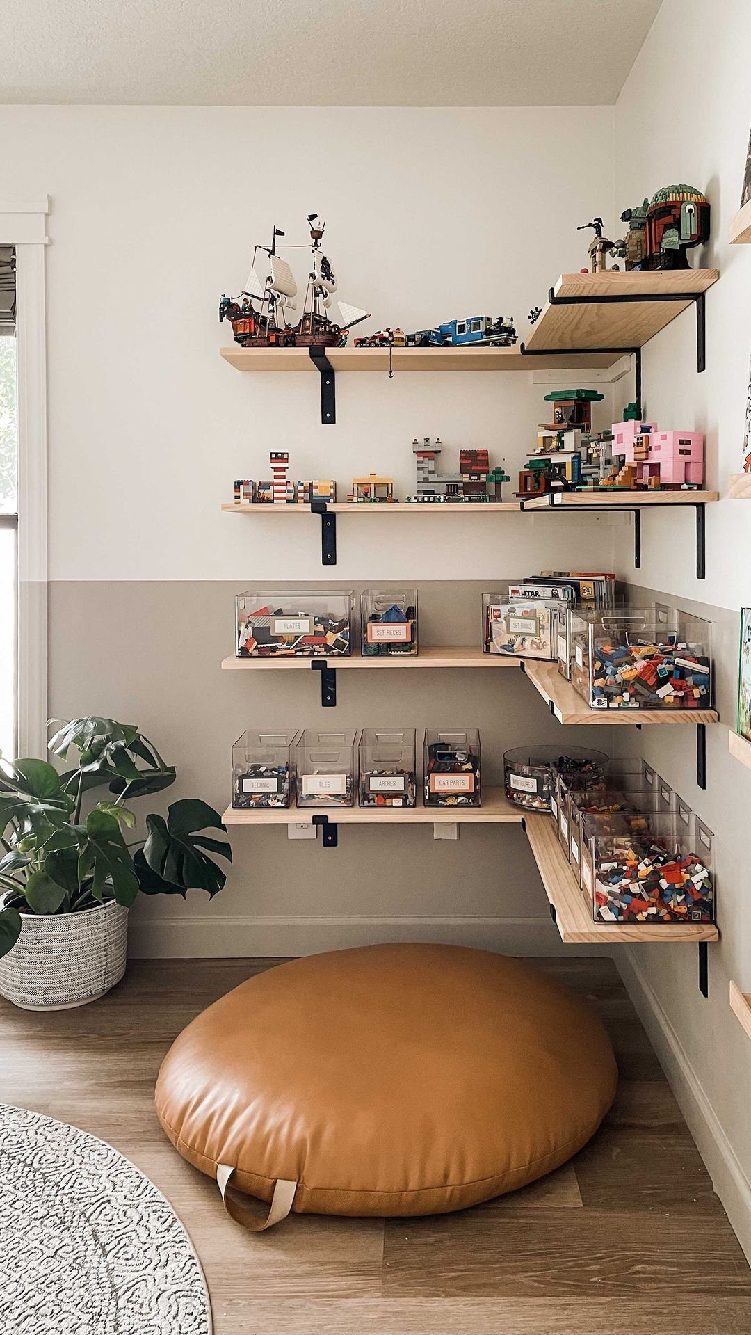 Wooden shelves holding LEGO sets and clear plastic containers filled with colorful LEGO bricks on a wall.
