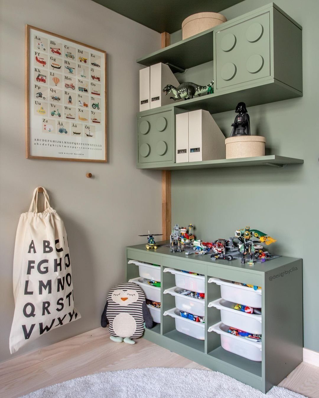Sage green storage unit with white open bins filled with colorful building blocks in a room.