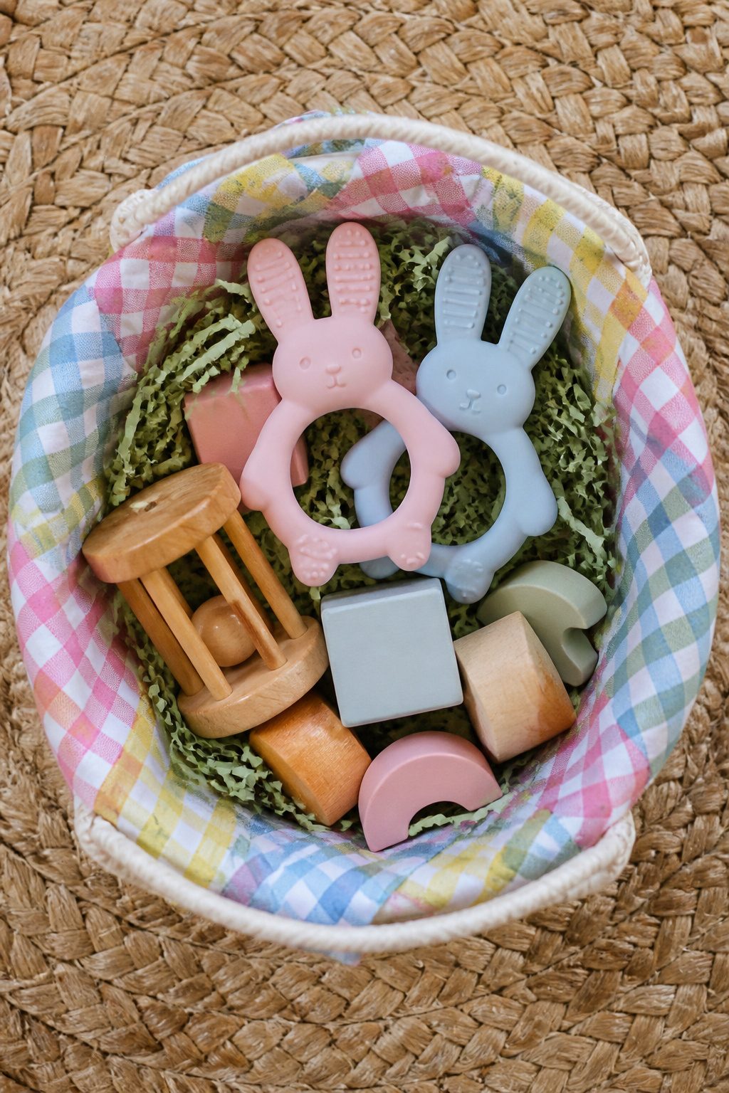 A basket featuring wooden toys and a silicone bunny teether.