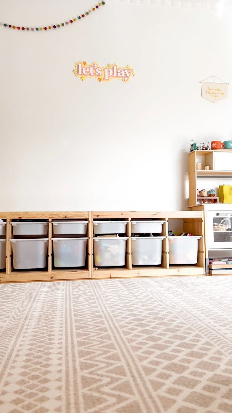 A cream patterned geometric rug covers the floor in a bright, organized playroom.