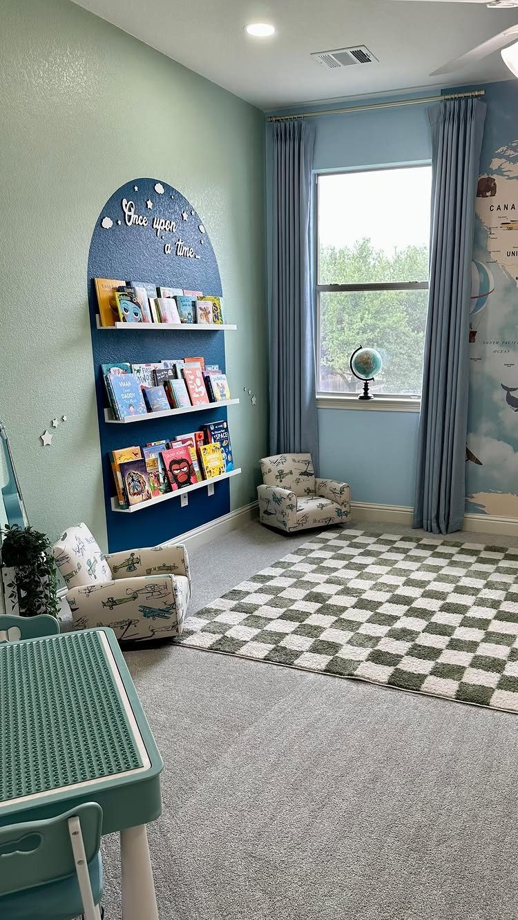 Blue arched bookshelf filled with books, two small armchairs, and a checkered rug in a bright playroom.