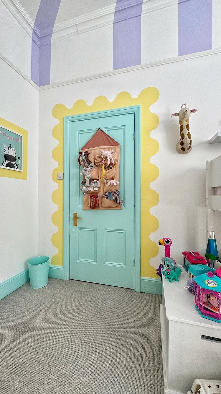 A turquoise door with a yellow wavy border and purple ceiling stripes in a playroom.
