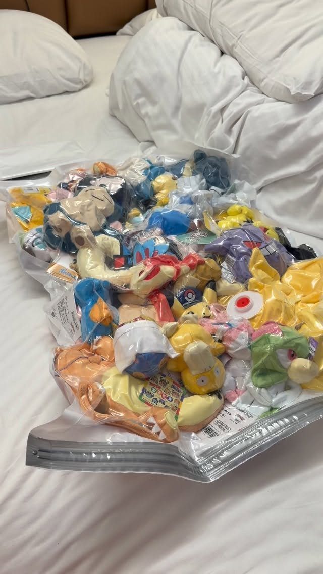 6 Plush Storage Ideas for Stuffed Toys That Clear Floor Pile-Ups 5 A large clear plastic vacuum seal bag filled with many colorful stuffed animals on a white bed.