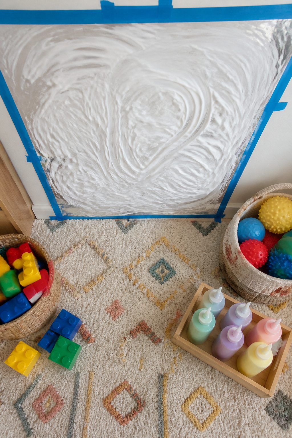 Contact paper with shaving cream applied for sensory play on a vertical surface.