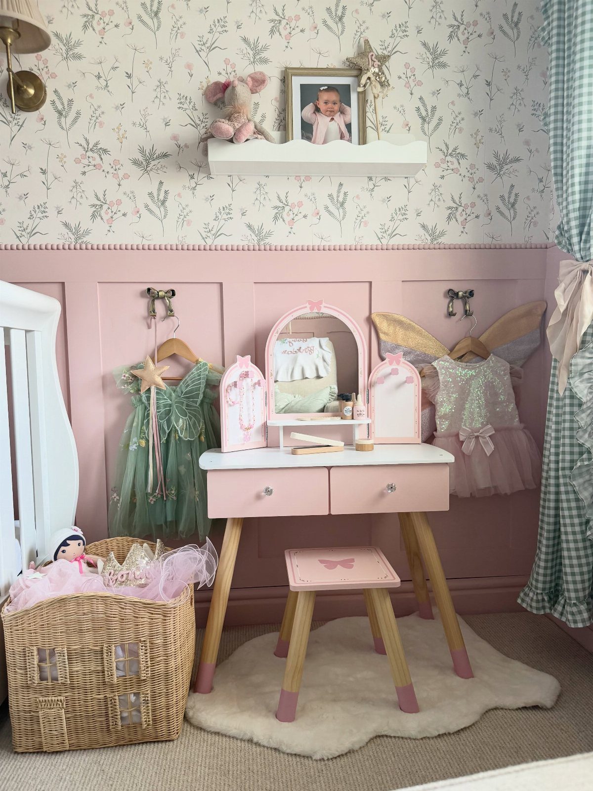 9 Small Play Area Ideas for Families Short on Space 5 Pink vanity table with costumes hanging on a pink paneled wall in a nursery.
