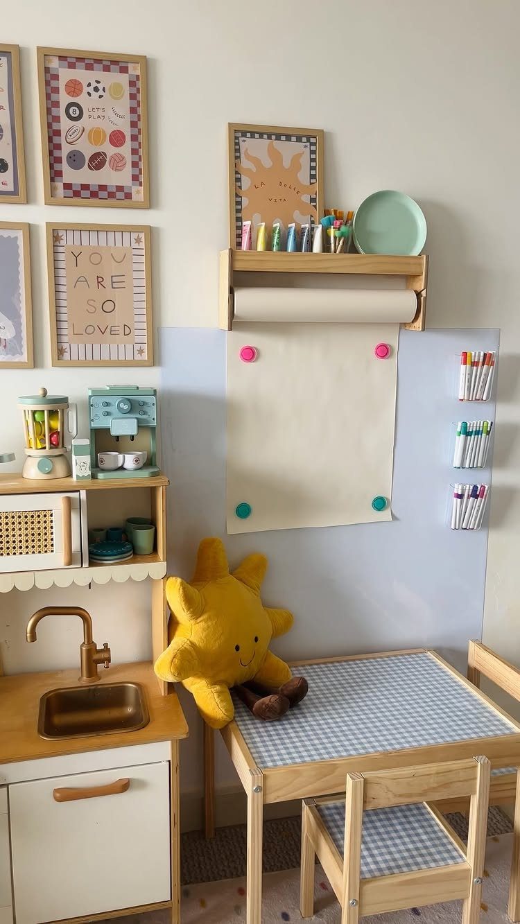 23 Small Playroom Design Ideas That Fit Real Rooms 20 A small wooden child's table with art supplies and a play kitchen in a playroom.