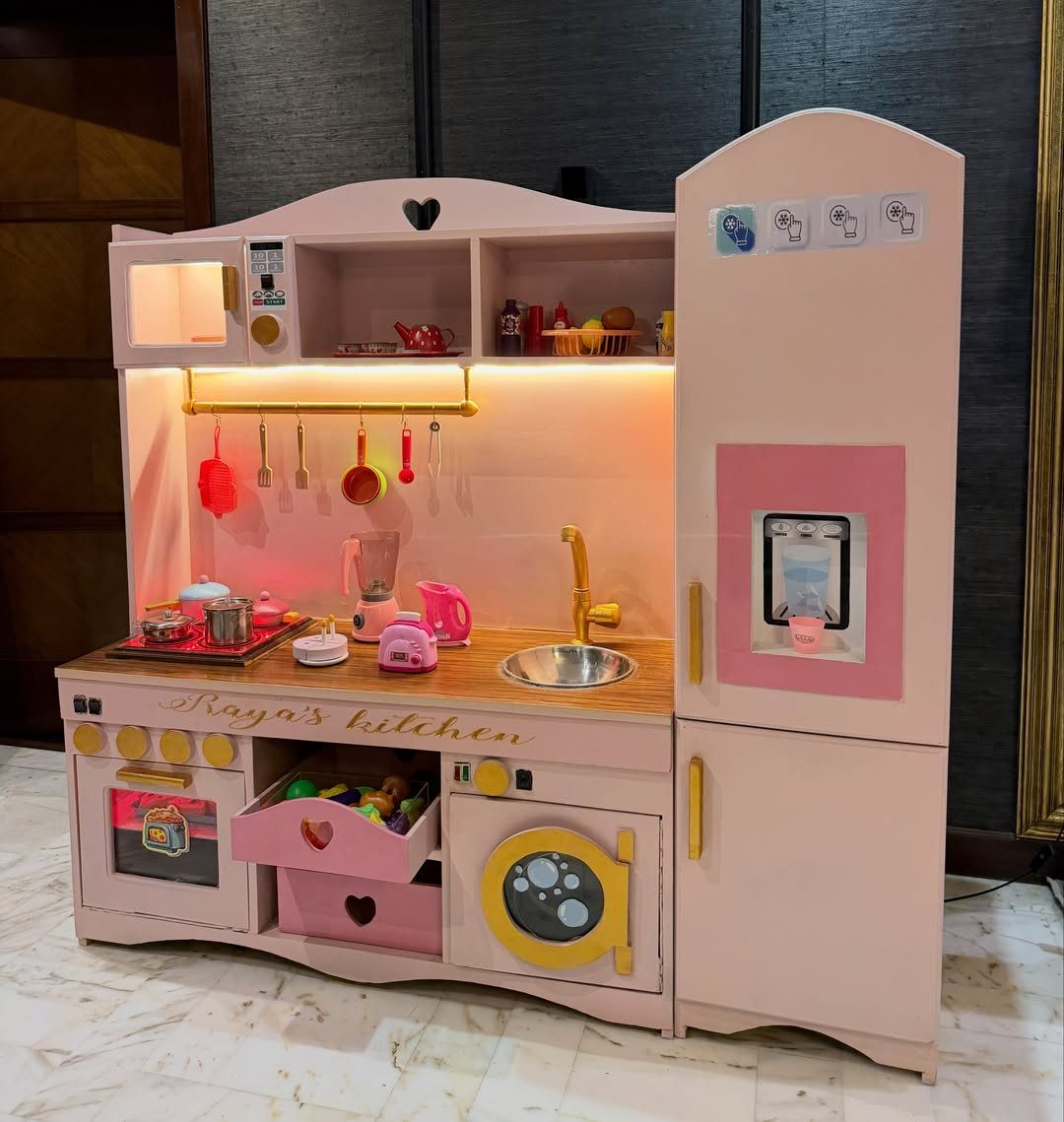 23 Small Playroom Design Ideas That Fit Real Rooms 8 Pink wooden toy play kitchen set with miniature accessories and warm lighting.