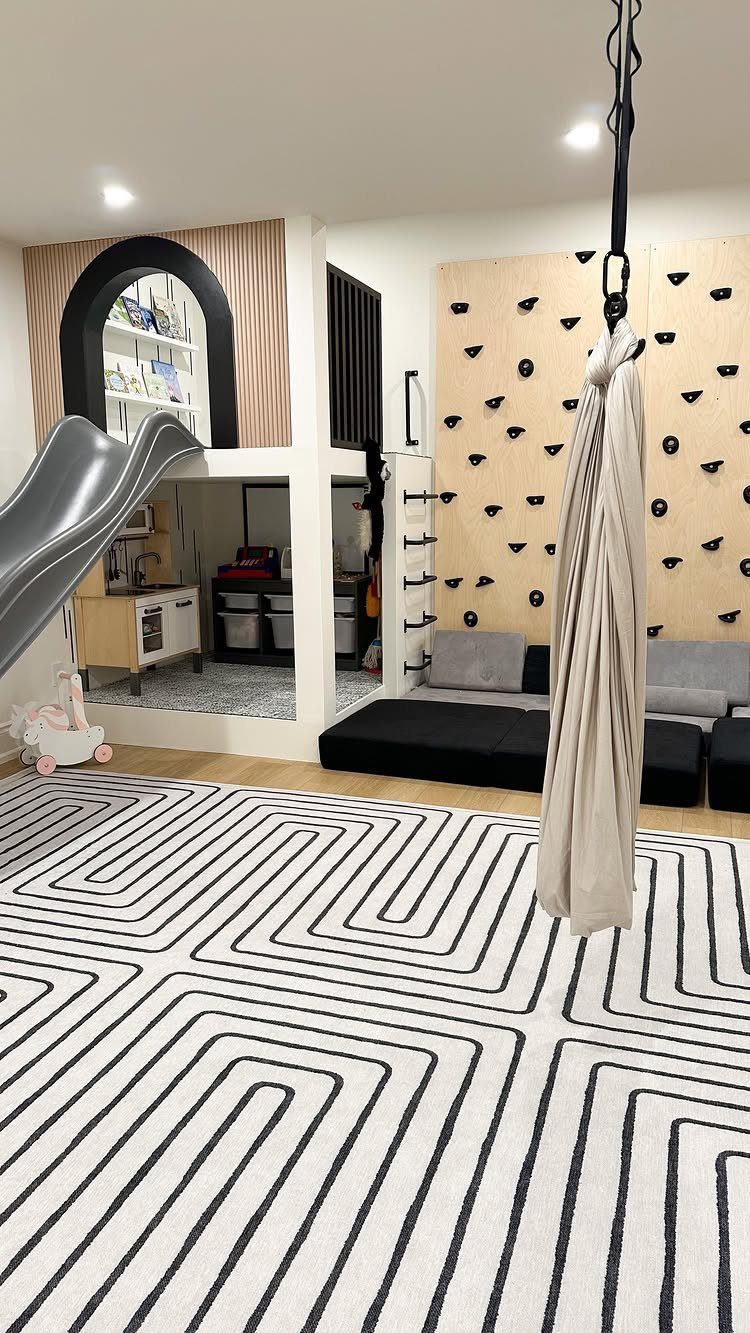 23 Small Playroom Design Ideas That Fit Real Rooms 6 Children's playroom with a climbing wall, slide, play kitchen, and geometric rug.