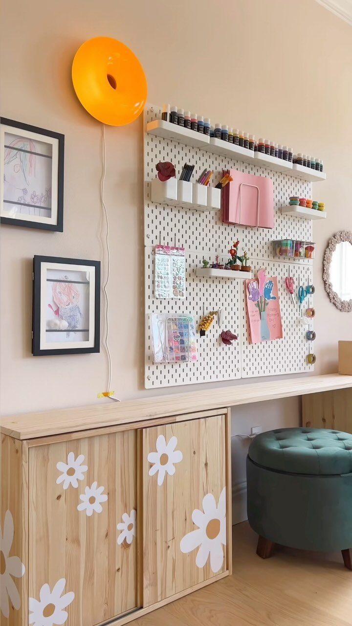 23 Small Playroom Design Ideas That Fit Real Rooms 16 A wooden craft table with daisy decorations and a white pegboard holding art supplies.
