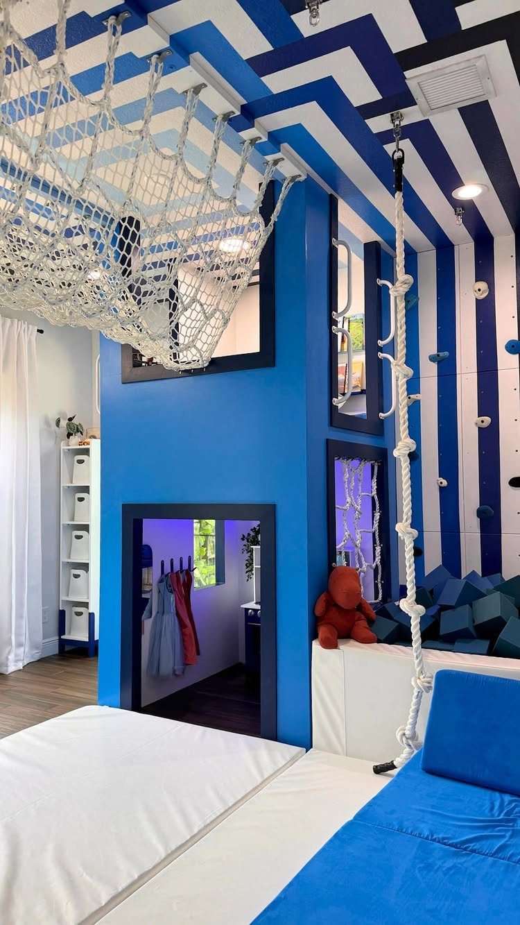 23 Small Playroom Design Ideas That Fit Real Rooms 19 Blue and white striped playroom walls with a large white rope net hanging from the ceiling.