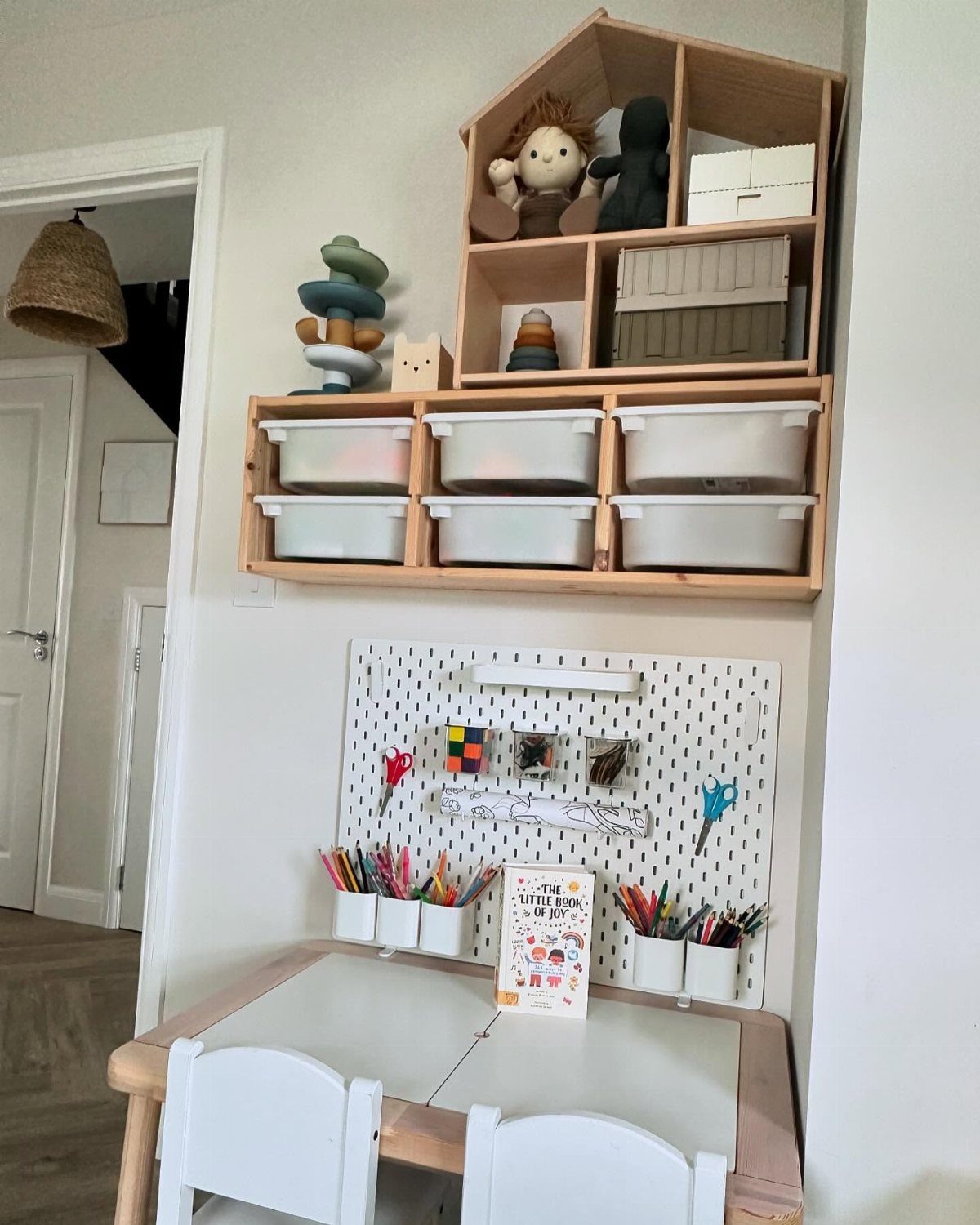 23 Small Playroom Design Ideas That Fit Real Rooms 13 White pegboard holding art supplies mounted on a wall above a small child's table.