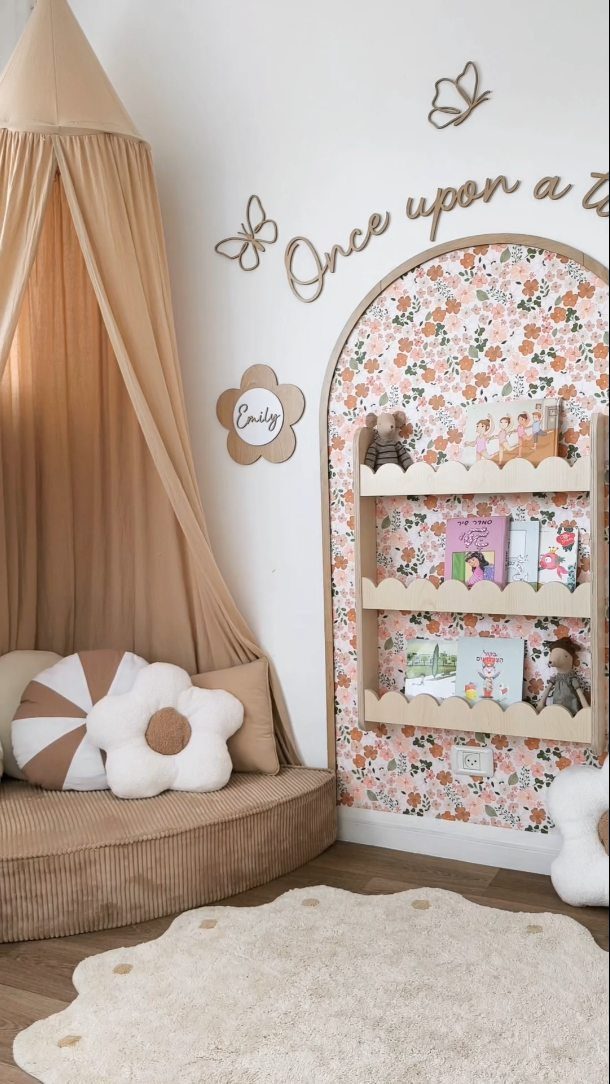 23 Small Playroom Design Ideas That Fit Real Rooms 2 A cozy reading nook with a tan canopy, flower pillows, and floral bookshelves filled with books.