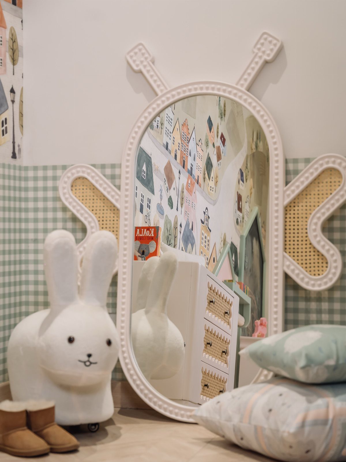 23 Small Playroom Design Ideas That Fit Real Rooms 14 Oval white butterfly-shaped mirror reflecting a playroom with a bunny chair and patterned wallpaper.