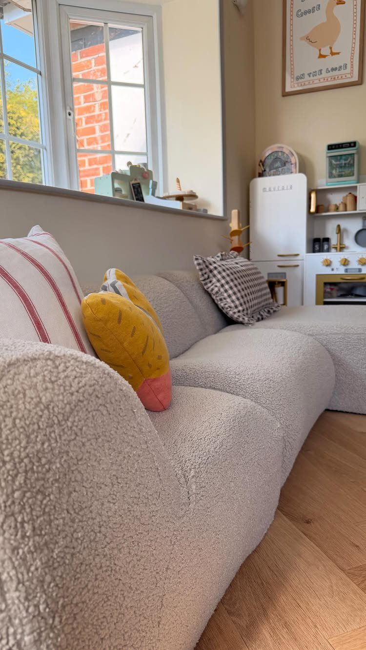 Cream bouclé sofa with colorful pillows in a bright room with a play kitchen.