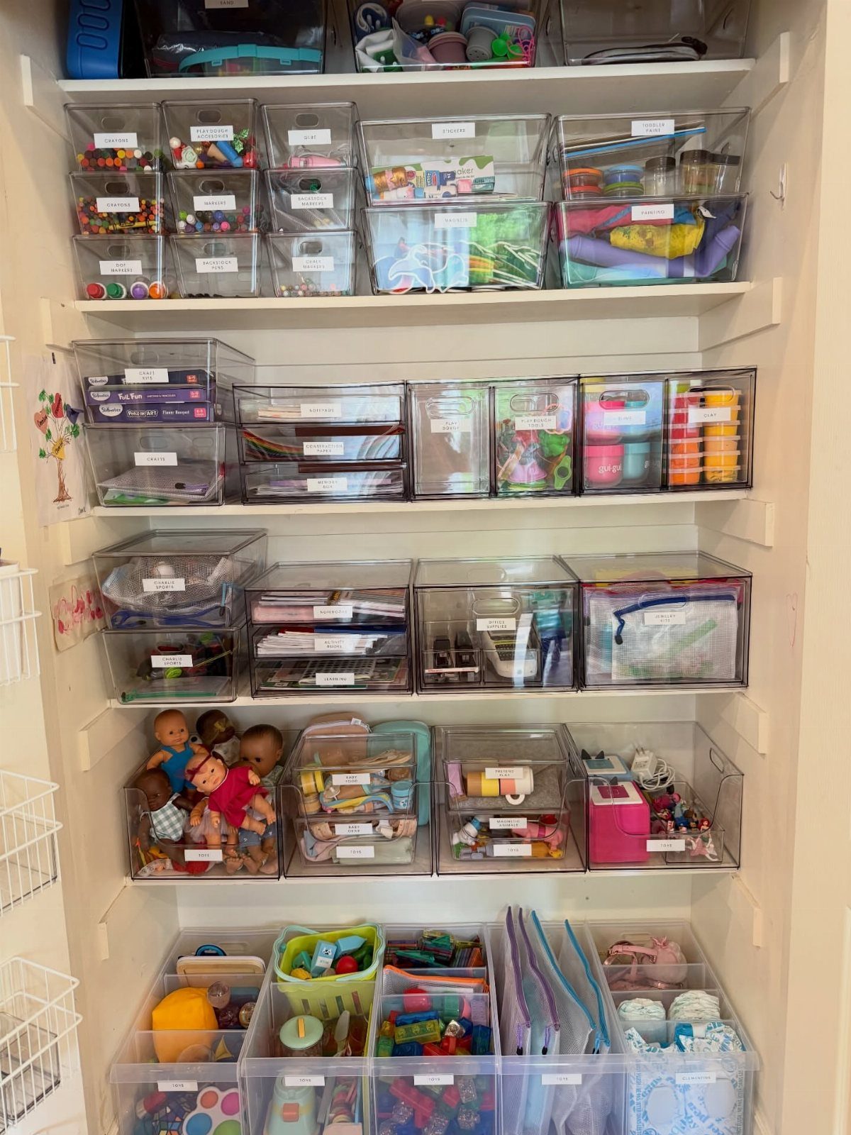 7 Toy Organization Ideas for Playrooms and Living Spaces 6 White shelves filled with clear plastic bins containing various colorful toys and organized supplies.