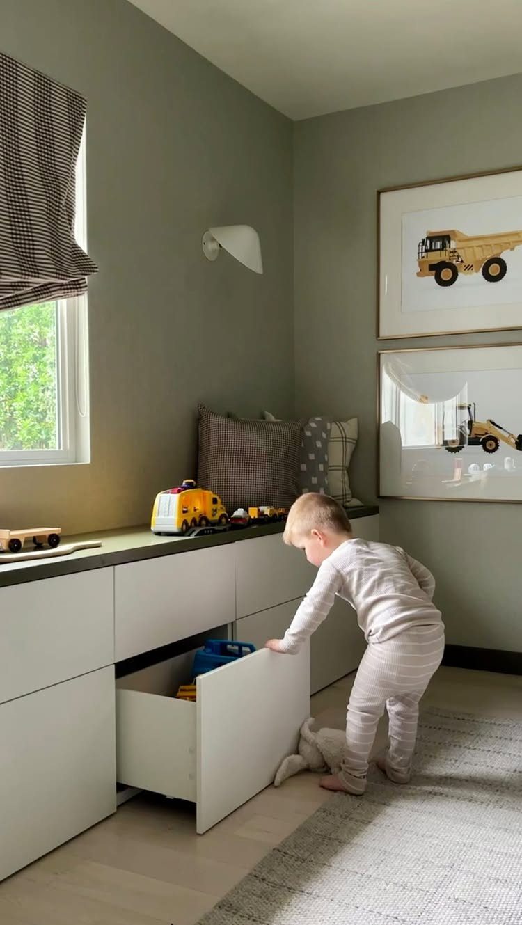 7 Toy Organization Ideas for Playrooms and Living Spaces 1 A toddler pulls open a large white drawer from a built-in playroom cabinet unit.