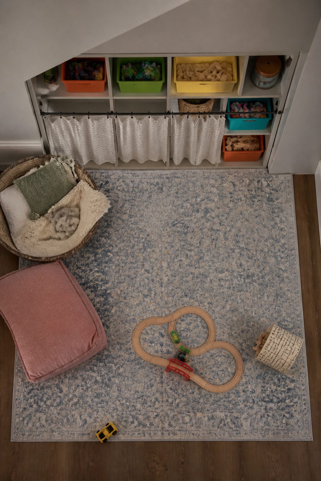 Storage area under stairs with built-in shelves and toy bins.